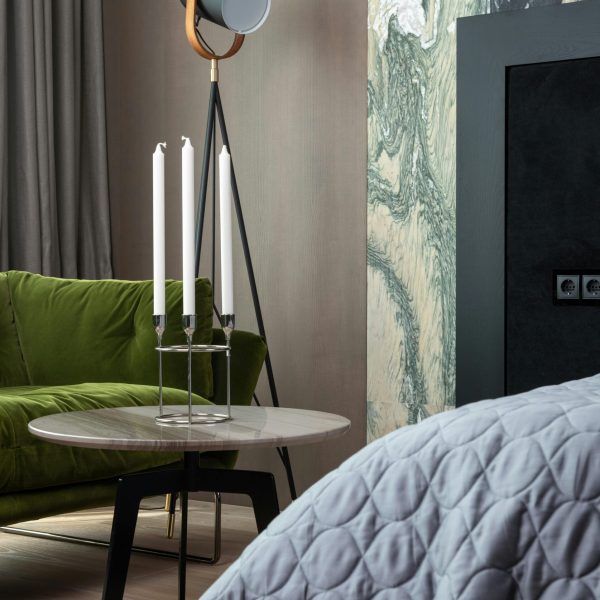 Small round coffee table with candlesticks near lamp and sofa in cozy living room